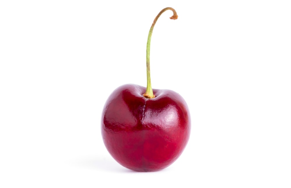 a single cherry with a stem on a white background
