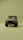 A vintage-style off-road vehicle is prominently displayed from the front on a minimalistic, uniform olive green background. The vehicle is tan with a sturdy frame, circular headlights, and rugged tires, creating a sense of adventure and durability.