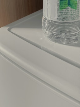 A serene morning scene with a bottle of luteal tint supplements beside a glass of water on a white countertop bathed in soft natural light.