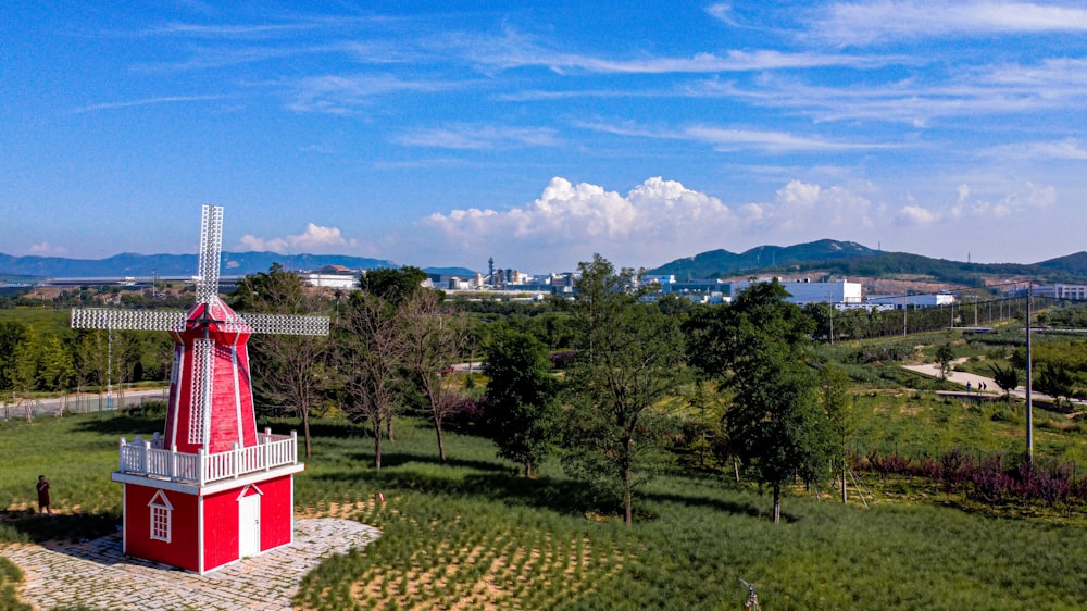 a red and white windmill in a green field