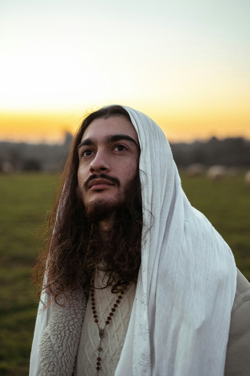 a man with long hair wearing a white shawl