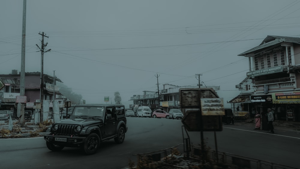 a black jeep driving down a street next to tall buildings