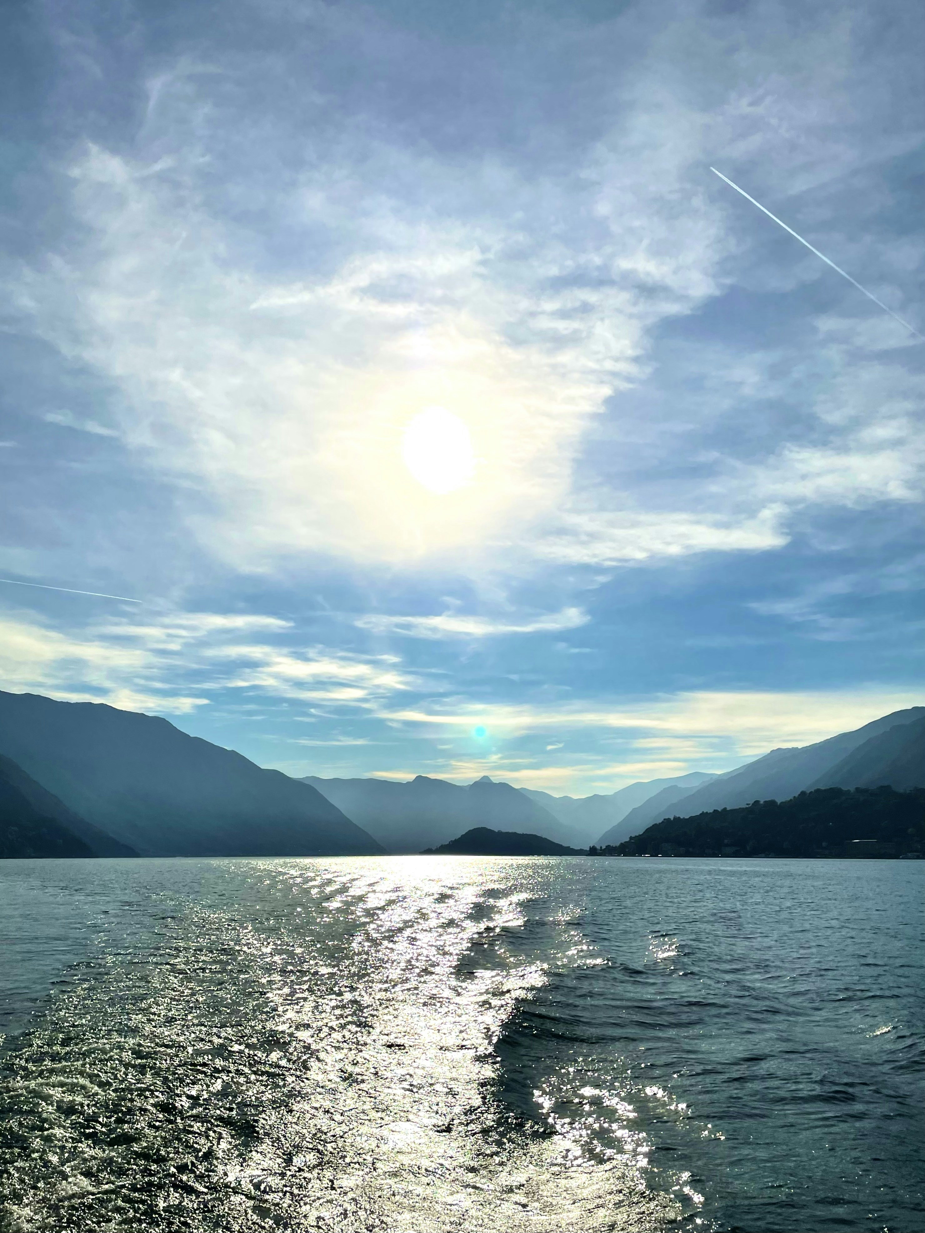 the sun is shining over the water and mountains