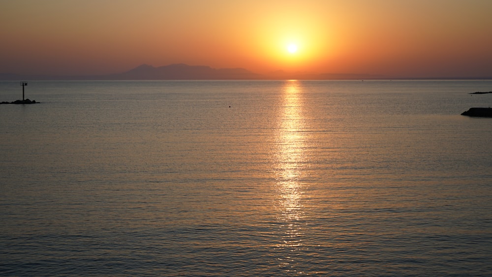 una gran masa de agua con una puesta de sol en el fondo