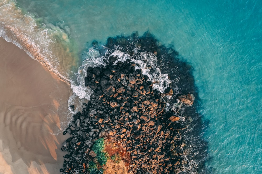 an aerial view of a beach with rocks and water