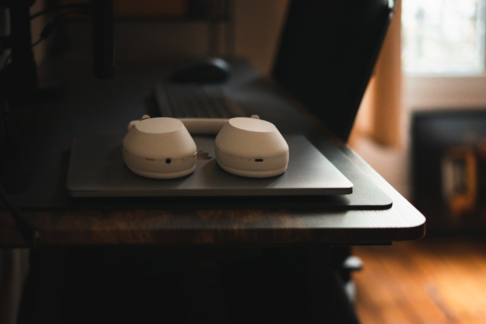 a pair of white headphones sitting on top of a wooden table