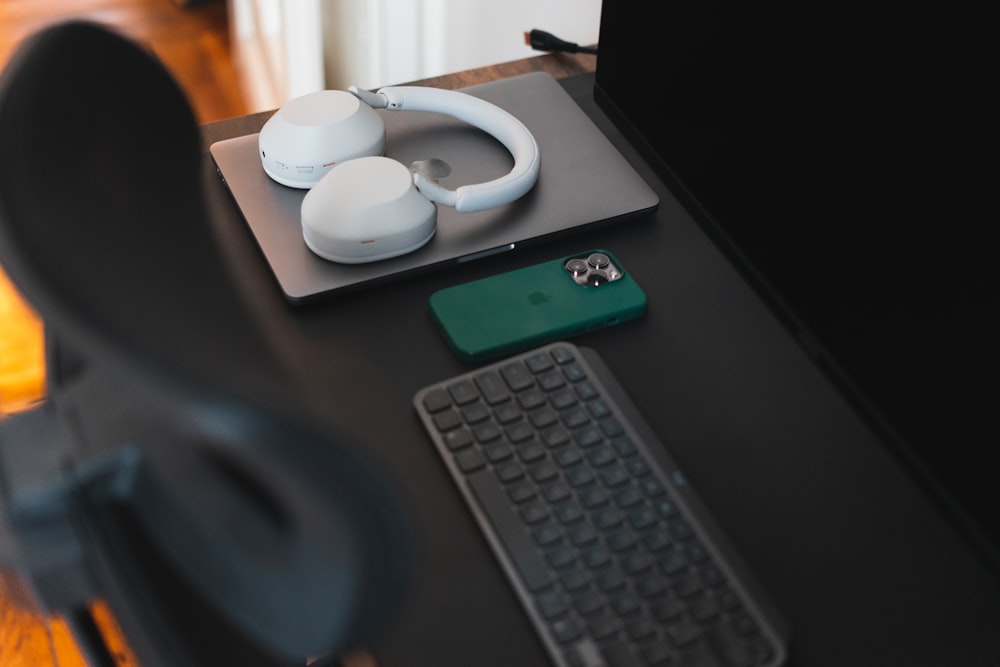 a desk with a keyboard, mouse and headphones on it