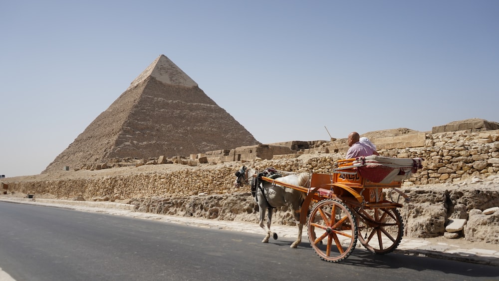 uma carruagem puxada por cavalos na frente de uma pirâmide