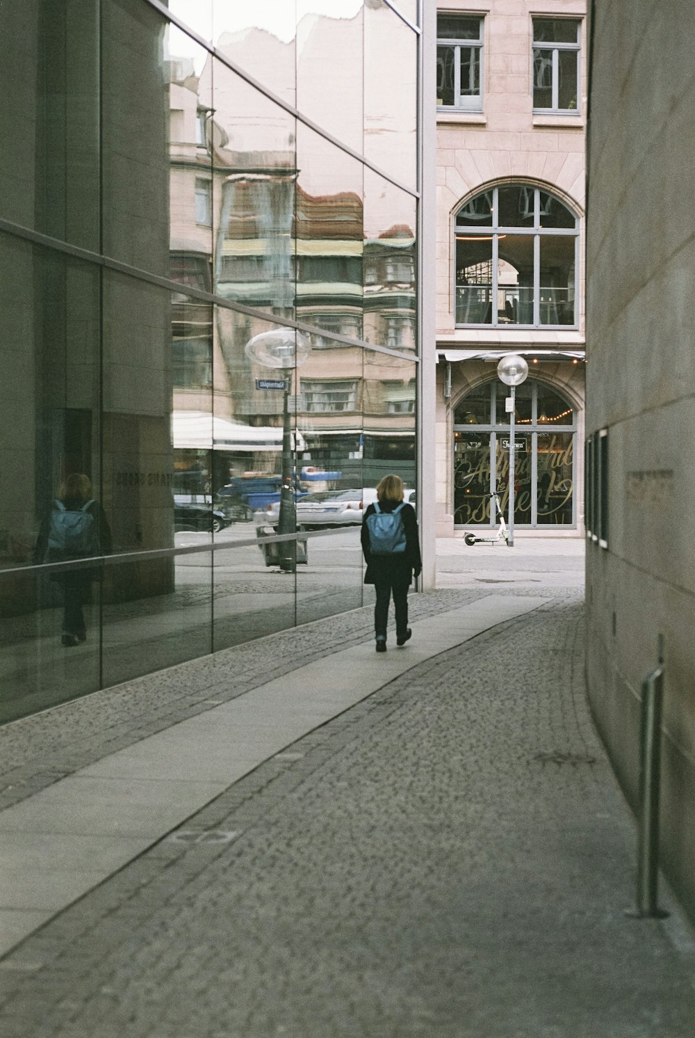 a man walking down a street next to a tall building