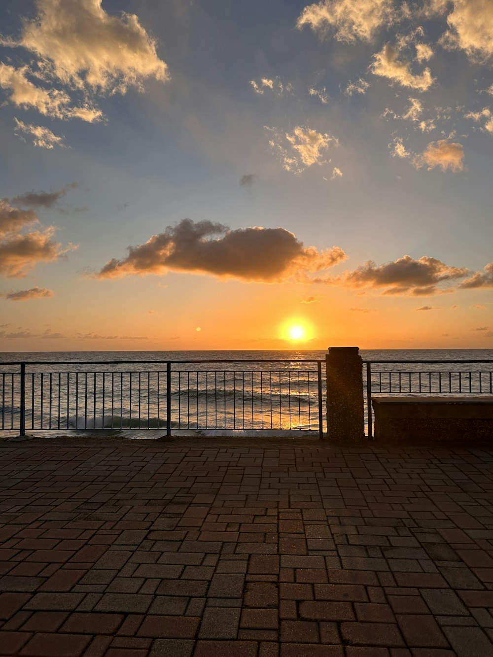 the sun is setting over the ocean from a pier