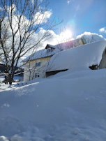 A cozy Canadian-style house with snow gently resting on the roof under a clear blue sky.