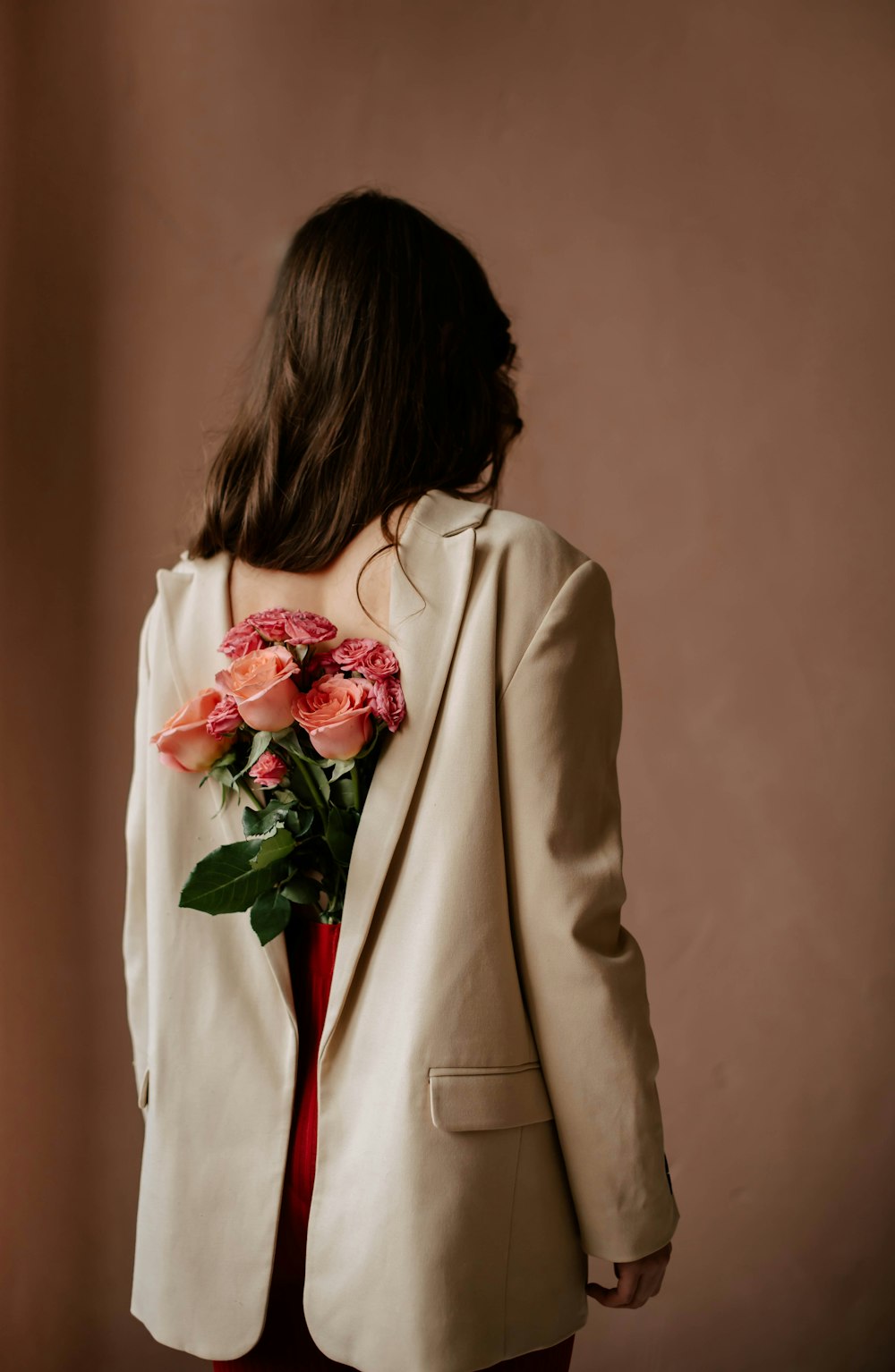 a woman in a suit holding a bouquet of flowers