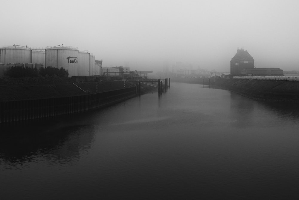 a black and white photo of a foggy river
