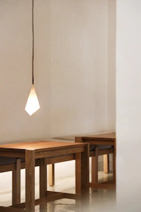 A sleek Scandinavian acrylic pendant light glowing softly over a minimalist dining table.