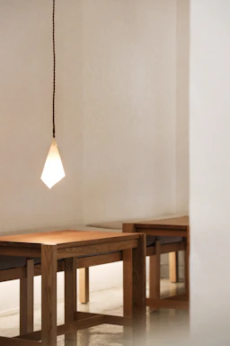 A sleek pendant light hanging over a minimalist dining table in a cozy room.