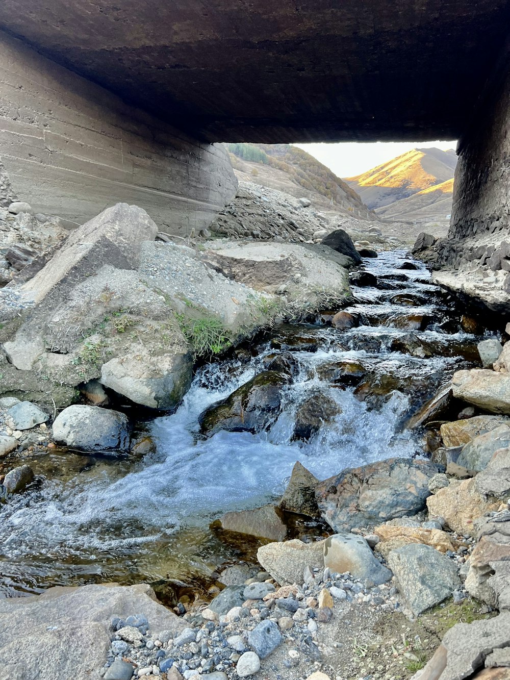 a river running under a bridge next to rocks