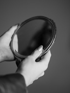 An antique mirror reflecting a pair of entwined hands, capturing a moment of tension and longing.