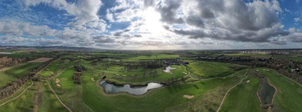 Aerial shot of a golf course winding along a riverbank with surrounding hills.