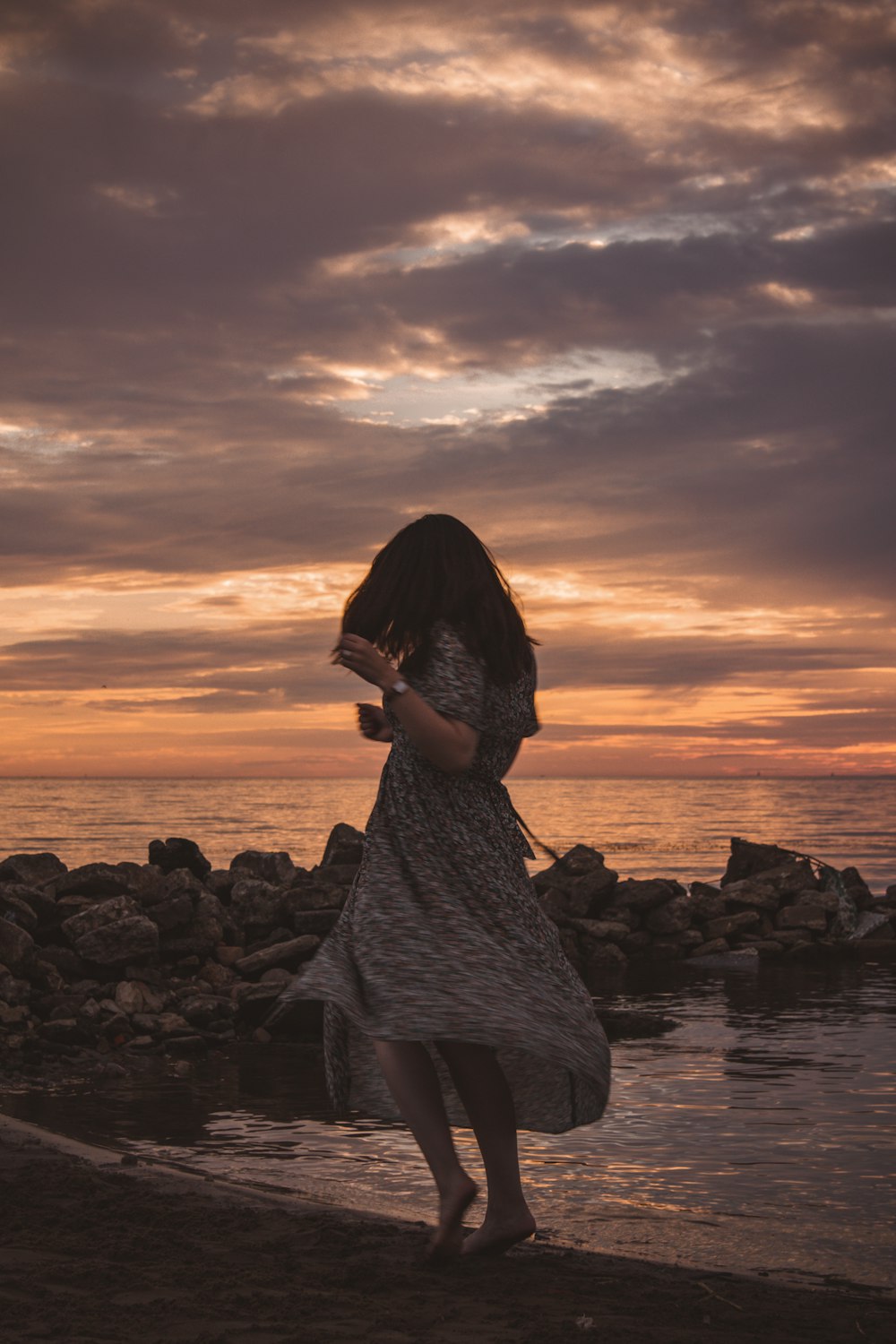 a woman standing on a beach next to a body of water