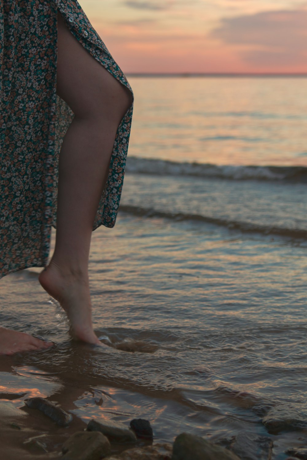 a person walking on the beach at sunset