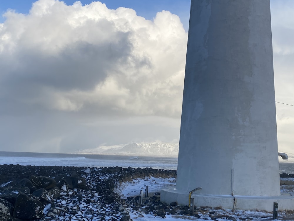 a large white lighthouse sitting on top of a rocky beach