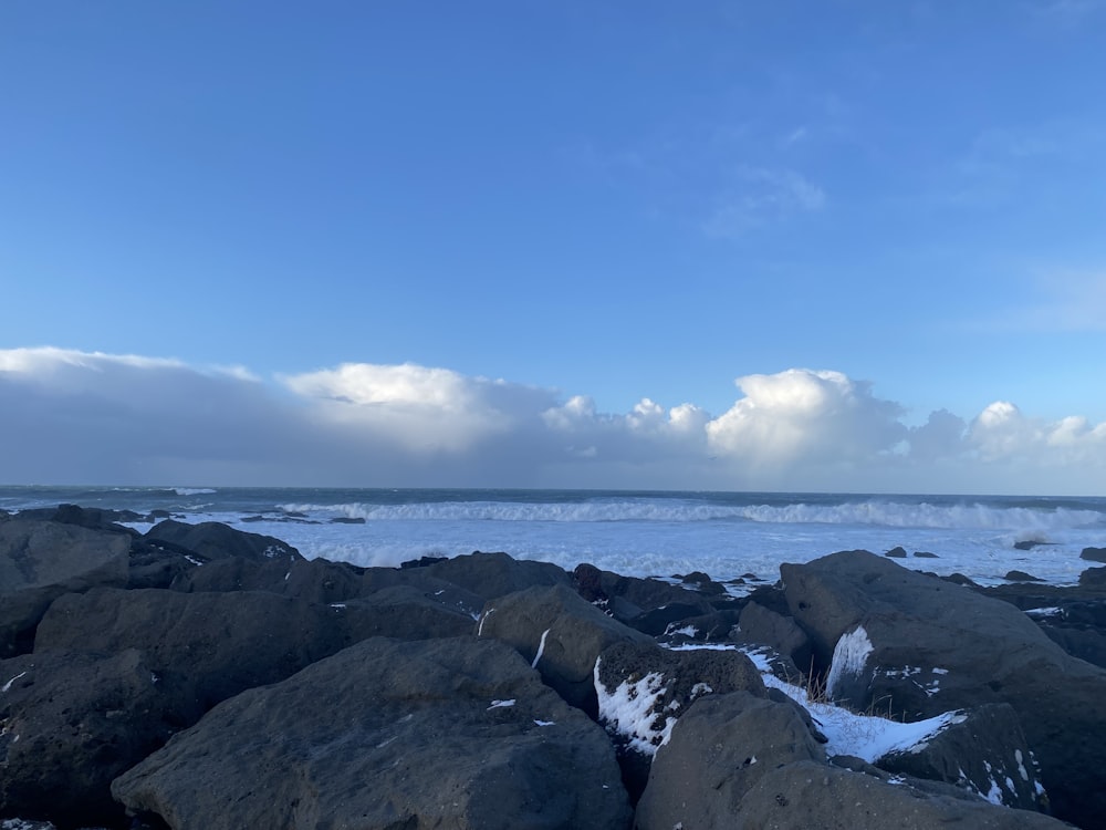 a view of a rocky beach with waves coming in