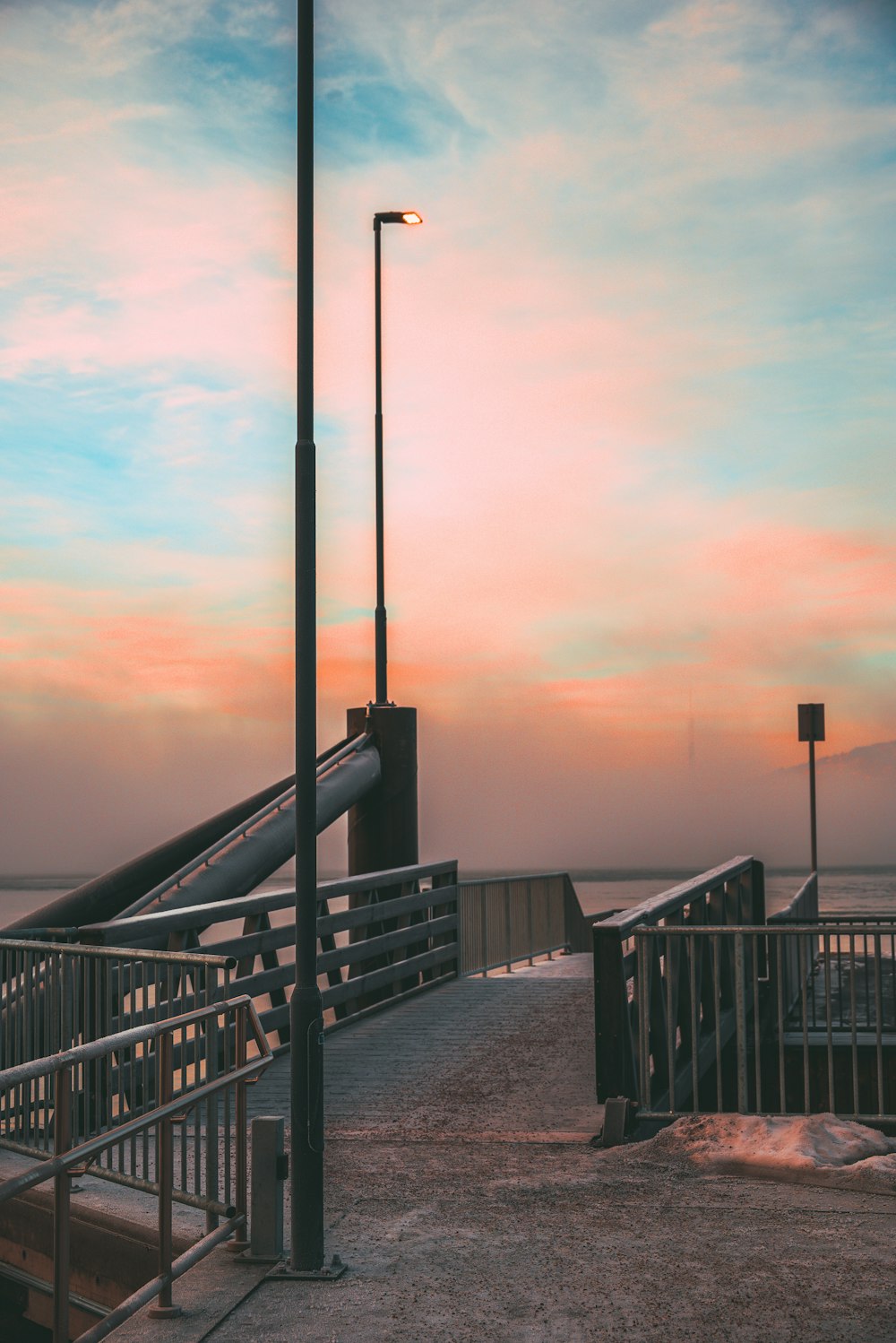 a bench sitting on top of a pier next to the ocean