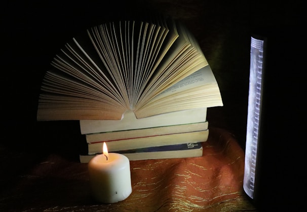 An open book with notes and a candle, symbolizing study.