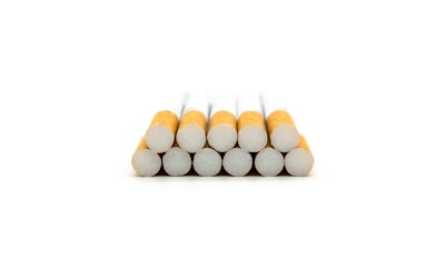 A stack of twelve cigarettes arranged in a pyramid formation with the filters facing forward.