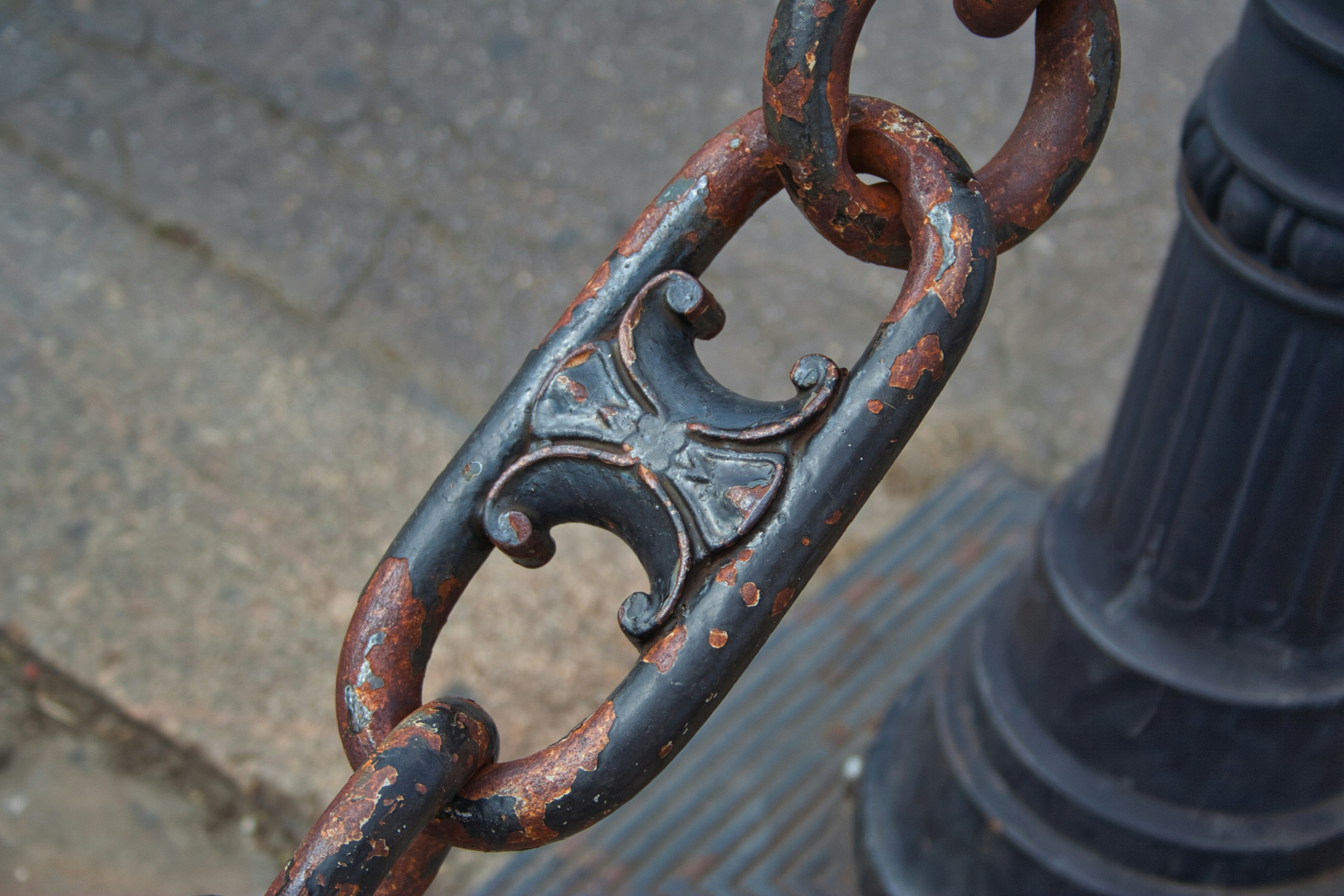 a rusted metal pole with a chain attached to it
