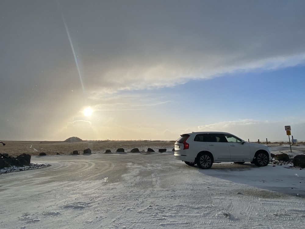 a white suv is parked on a snowy road