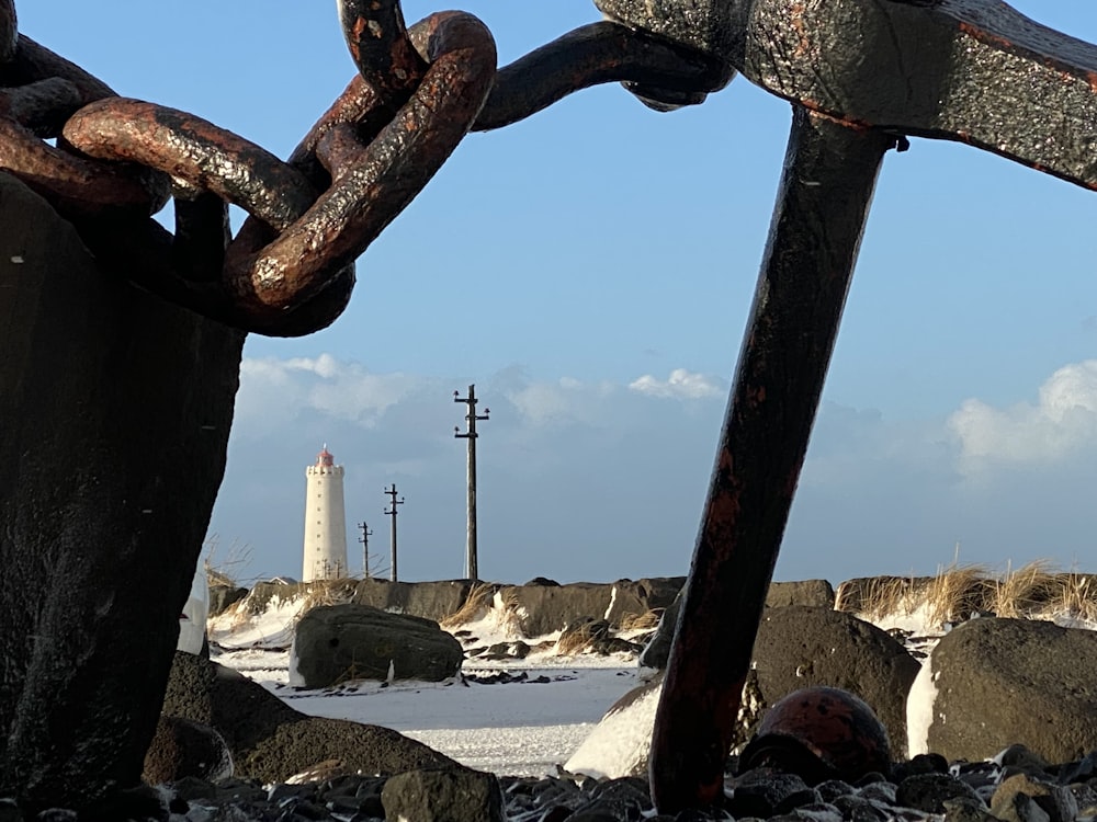 a rusty chain with a lighthouse in the background