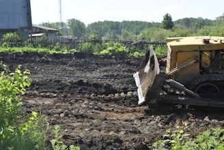 a bulldozer digging through a field of dirt