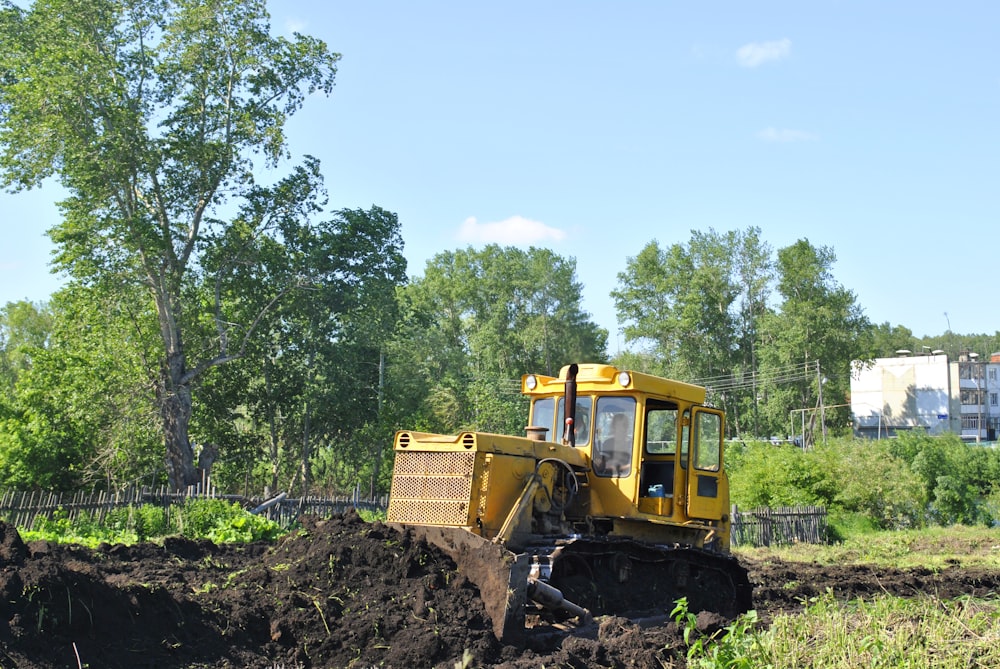 Ein Bulldozer gräbt sich durch ein Feld mit Bäumen im Hintergrund