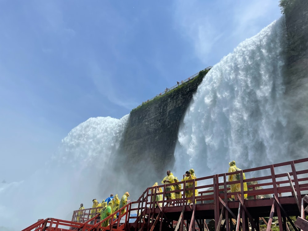 a group of people standing on a bridge near a waterfall