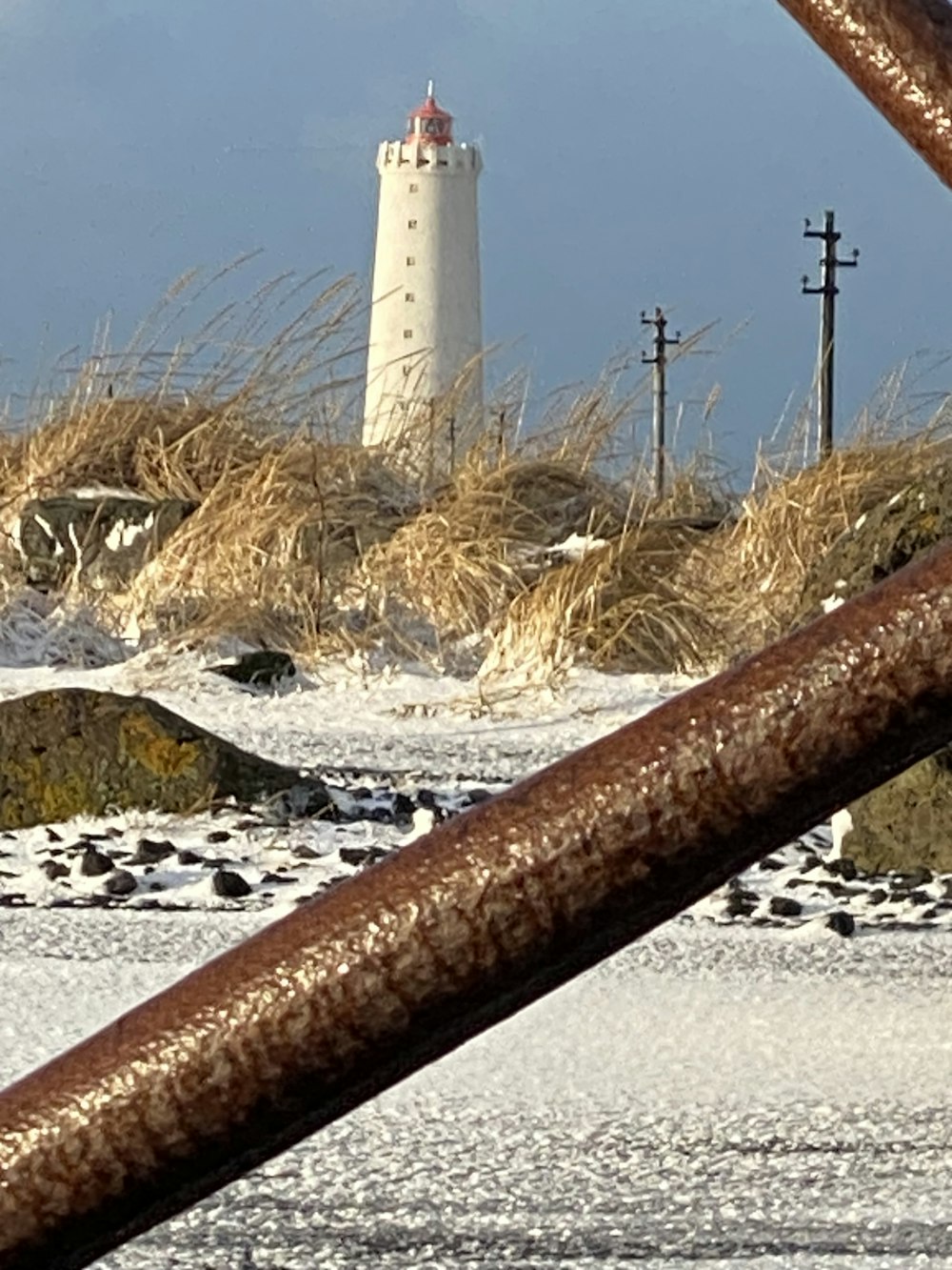 a view of a lighthouse through a rusty fence