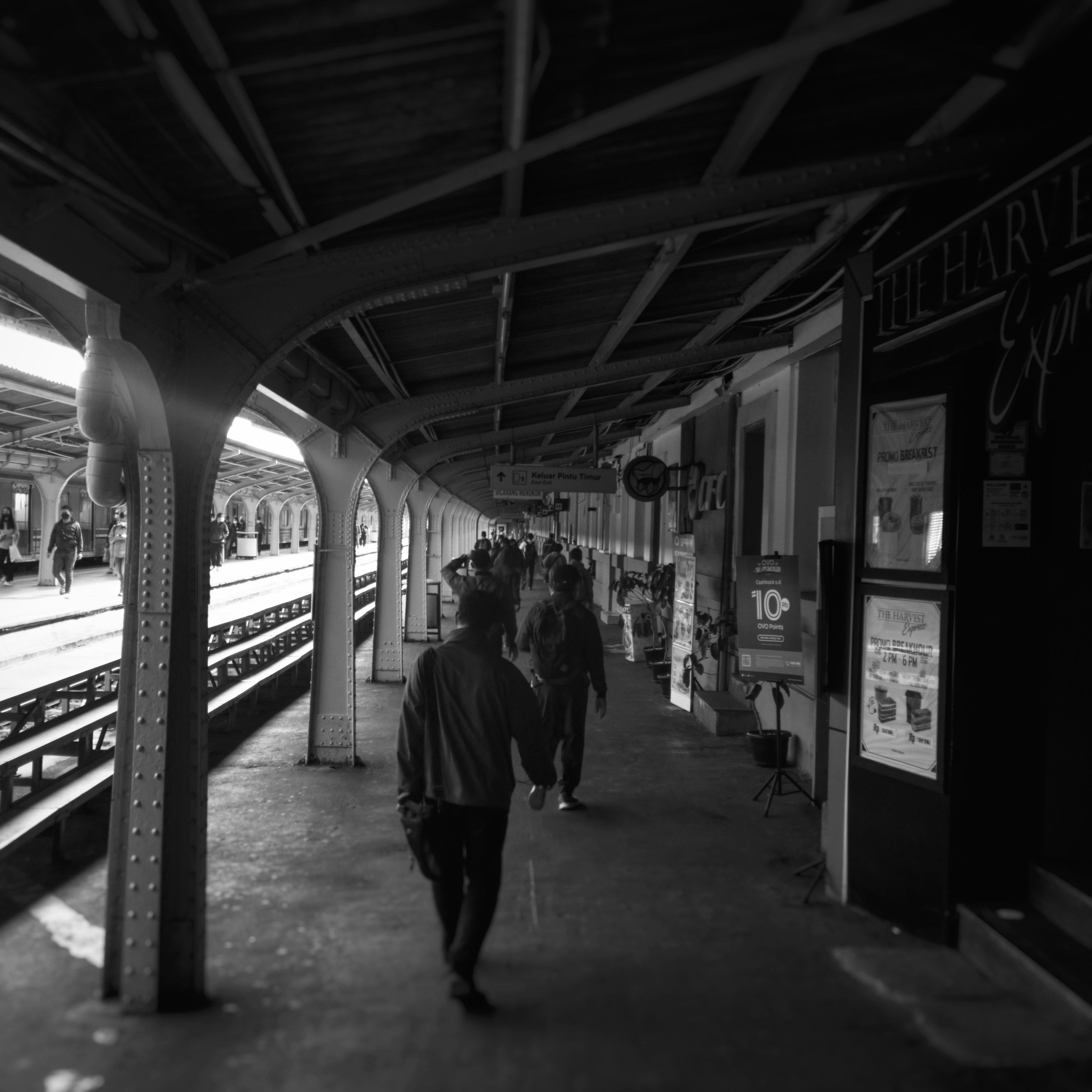 a black and white photo of people walking on a train platform
