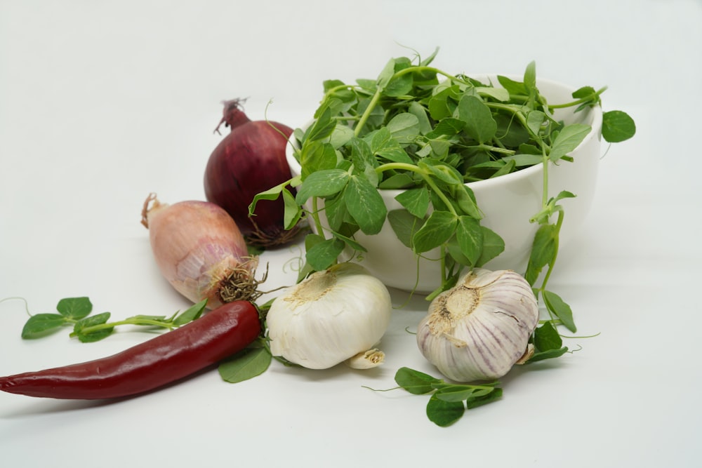 a white bowl filled with vegetables next to a red pepper