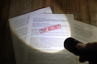 Hands carefully handling confidential documents with a secure lockbox in the background.