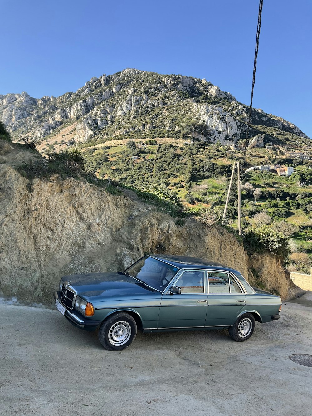 a blue car parked in front of a mountain