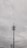 A tall communication tower with multiple antennas and cables is set against a cloudy sky. The tower features linear and dish components near the top, with surrounding power lines visible in the foreground.