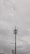 A tall communication tower with multiple antennas and cables is set against a cloudy sky. The tower features linear and dish components near the top, with surrounding power lines visible in the foreground.