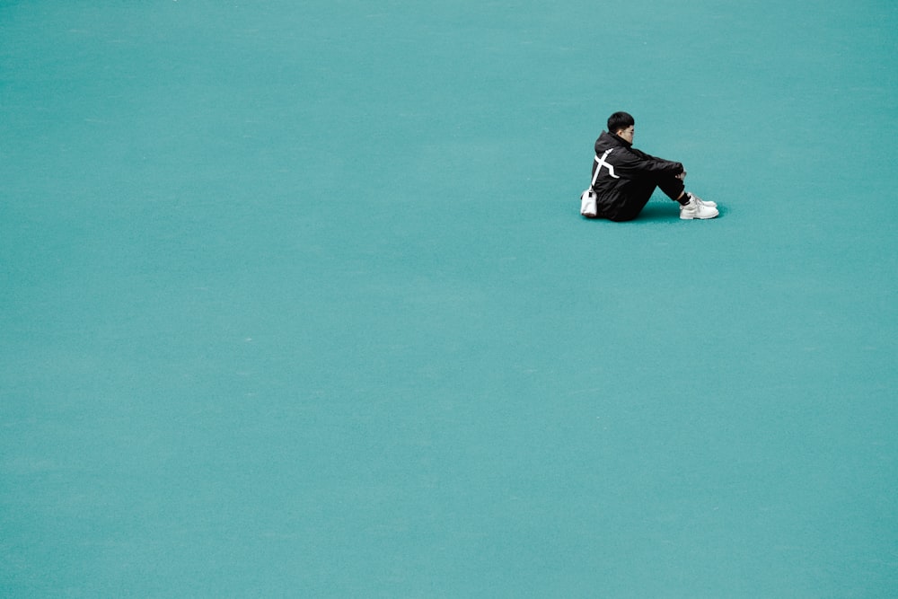 a person sitting on a tennis court with a tennis racket