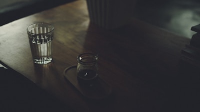 A serene morning scene with a person enjoying a glass of water alongside a Velinara supplement bottle on a wooden table.