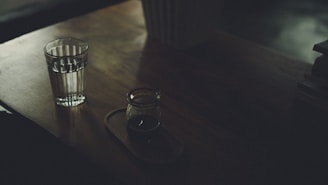 A serene morning scene with a person enjoying a glass of water alongside a Velinara supplement bottle on a wooden table.