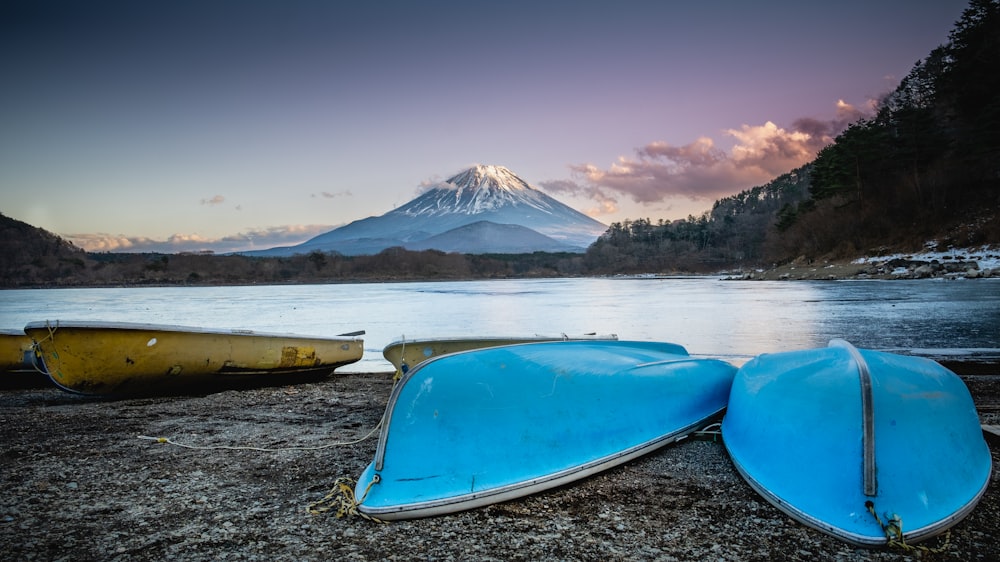 two canoes are sitting on the shore of a lake