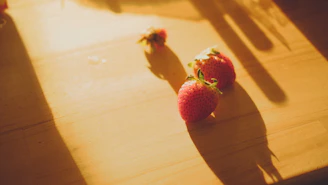 Rows of strawberries carefully laid out on drying racks, bathed in warm golden light.