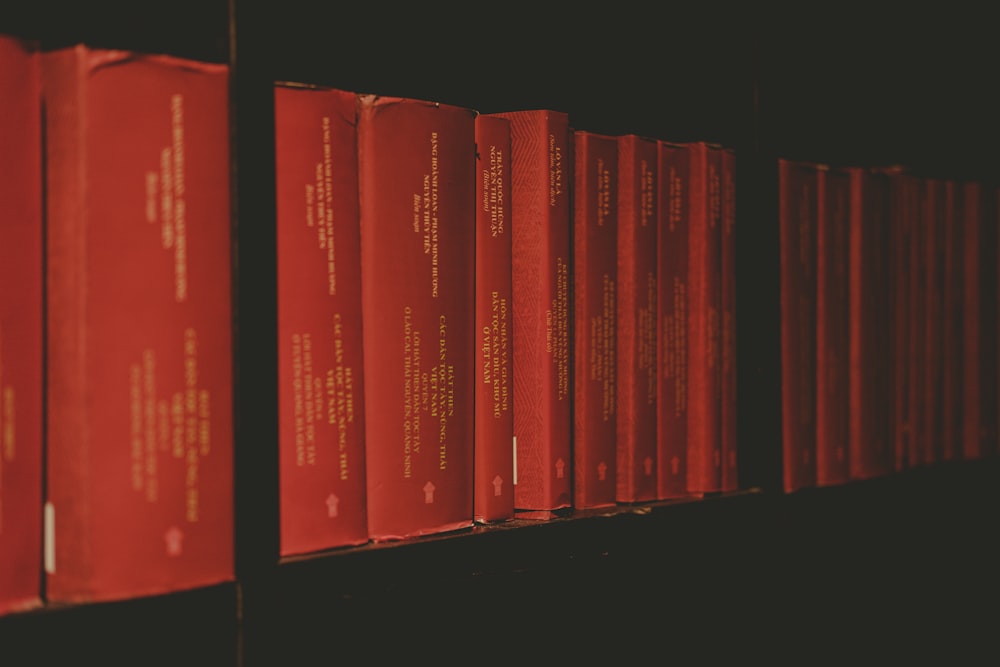 a row of red books sitting on top of a shelf
