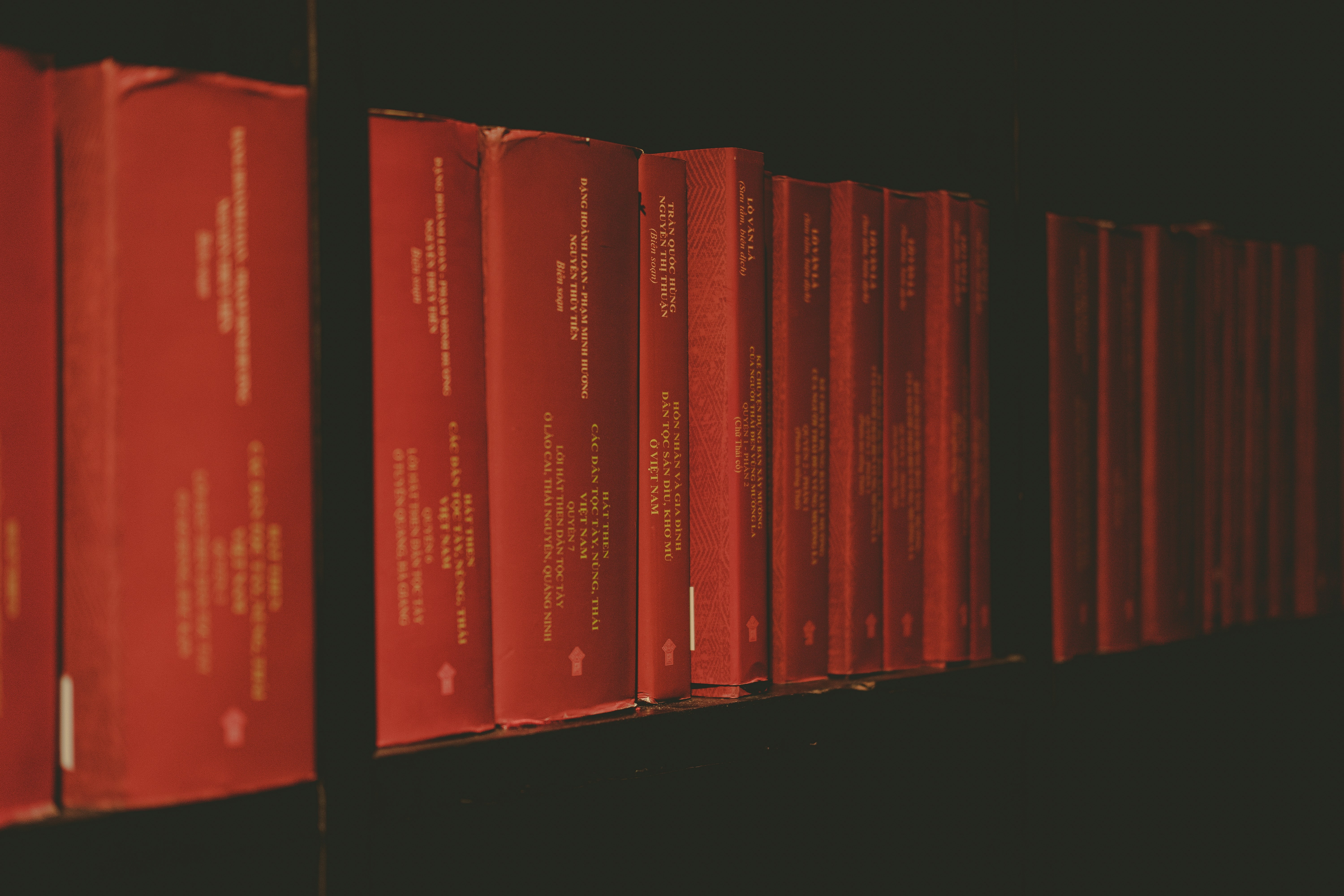 a row of red books sitting on top of a shelf