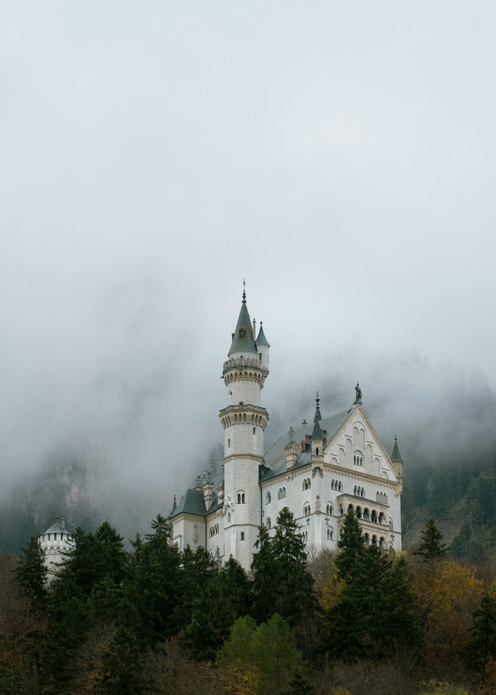 a large white castle sitting on top of a lush green hillside